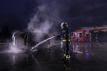 Image showing Firefighters fight the fire flame to control fire not to spreading out. Firefighter industrial and public safety concept. Traffic or car accident rescue and help action.