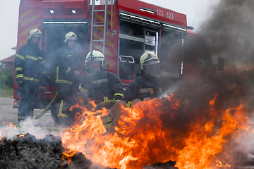 Image showing Firefighters fight the fire flame to control fire not to spreading out. Firefighter industrial and public safety concept. Traffic or car accident rescue and help action.