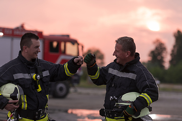 Image showing Fireman using walkie talkie at car traffic rescue action fire truck and fireman's team in background.