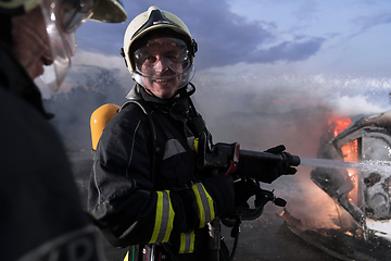 Image showing Firefighters fight the fire flame to control fire not to spreading out. Firefighter industrial and public safety concept. Traffic or car accident rescue and help action.