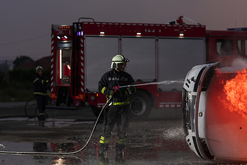 Image showing Firefighters fight the fire flame to control fire not to spreading out. Firefighter industrial and public safety concept. Traffic or car accident rescue and help action.