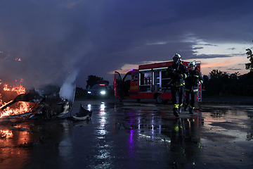 Image showing Firefighters fight the fire flame to control fire not to spreading out. Firefighter industrial and public safety concept. Traffic or car accident rescue and help action.