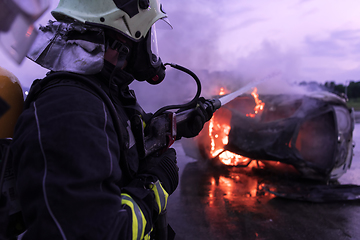 Image showing Firefighters fight the fire flame to control fire not to spreading out. Firefighter industrial and public safety concept. Traffic or car accident rescue and help action.