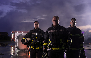 Image showing Brave Firefighters Team Walking to the Camera. In Background Paramedics and Firemen Rescue Team Fight Fire in Car Accident, Insurance and Save Peoples Lives concept.