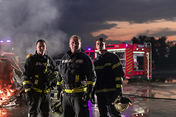 Image showing Brave Firefighters Team Walking to the Camera. In Background Paramedics and Firemen Rescue Team Fight Fire in Car Accident, Insurance and Save Peoples Lives concept.