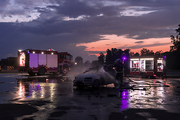 Image showing Firefighters fight the fire flame to control fire not to spreading out. Firefighter industrial and public safety concept. Traffic or car accident rescue and help action.