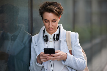 Image showing Woman, phone and social media with communication outdoor, chat or email with headphones, travel to work and mockup space. Young creative in city, mobile app with technology and 5g network in Boston