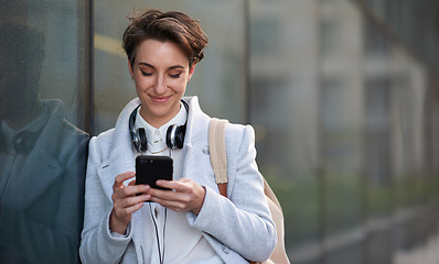 Image showing Woman, smartphone and social media with communication in city, chat or email with headphones, travel to work and mockup space. Young creative outdoor, smile at online post with technology in Boston