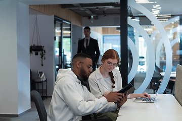 Image showing In a modern office African American young businessman and his businesswoman colleague, with her striking orange hair, engage in collaborative problem-solving sessions