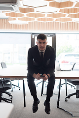 Image showing A businessman sitting on his desk, taking a moment to rest and unwind from a demanding workday, displaying a sense of tranquility and relaxation amidst the corporate environment