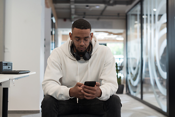 Image showing In a modern office setting, an African American businessman is diligently working on his laptop, embodying determination, ambition, and productivity in his professional environmen