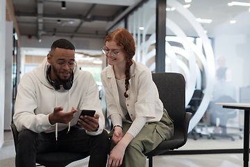 Image showing In a modern office African American young businessman and his businesswoman colleague, with her striking orange hair, engage in collaborative problem-solving sessions