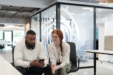 Image showing In a modern office African American young businessman and his businesswoman colleague, with her striking orange hair, engage in collaborative problem-solving sessions