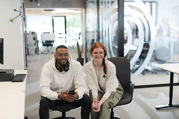 Image showing In a modern office African American young businessman and his businesswoman colleague, with her striking orange hair, engage in collaborative problem-solving sessions