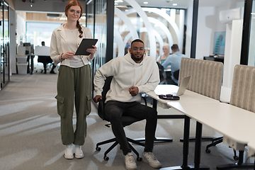 Image showing In a modern office African American young businessman and his businesswoman colleague, with her striking orange hair, engage in collaborative problem-solving sessions