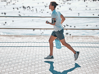 Image showing Cardio, fitness and man running on the promenade for training, health and workout by the beach. Exercise, sports and runner by the sea in the morning for jogging and outdoor sports for motivation