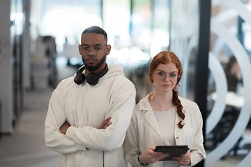 Image showing In a modern office African American young businessman and his businesswoman colleague, with her striking orange hair, engage in collaborative problem-solving sessions