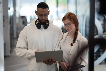 Image showing In a modern office African American young businessman and his businesswoman colleague, with her striking orange hair, engage in collaborative problem-solving sessions