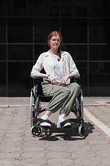 Image showing In front of a modern corporate building, a young woman sitting in a wheelchair confidently, symbolizing empowerment, inclusivity, and the strength to overcome challenges in the business world