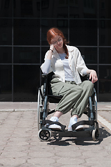 Image showing In front of a modern corporate building, a young woman sitting in a wheelchair confidently, symbolizing empowerment, inclusivity, and the strength to overcome challenges in the business world