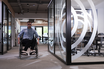 Image showing In a large modern corporation, a determined businessman in a wheelchair navigates through a hallway, embodying empowerment and inclusivity in the corporate world.