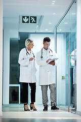 Image showing Tablet, collaboration and doctors talking planning a surgery in a modern hospital in discussion of diagnosis together. Man, woman and healthcare professionals brainstorming at a clinic using internet