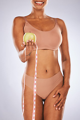 Image showing Woman, hands and apple with tape measure for healthy diet or weight loss against a gray studio background. Female in underwear holding fruit for slim dieting health, body care or wellness nutrition