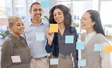 Image showing Business people, writing and schedule planning in strategy or brainstorming on glass wall at office. Happy group of designers in teamwork with smile for project plan, tasks or post it and sticky note