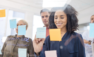 Image showing Black woman, smile and writing schedule in planning, strategy or brainstorming on glass wall at office. African American female designer in teamwork project plan, tasks or post it with sticky note