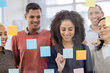 Image showing Black woman, writing and schedule planning with team in strategy or brainstorming on glass wall at office. African American female designer in teamwork project plan, tasks or post it with sticky note