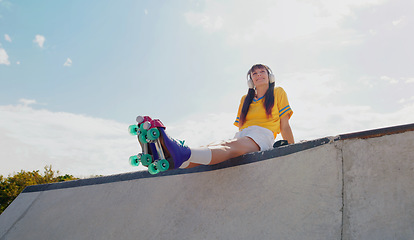 Image showing Sports, music and rollerblades with woman in skate park for summer break, streaming and mockup. Fitness, peace and skating with girl listening to headphones in outdoors for hobby, freedom and peace