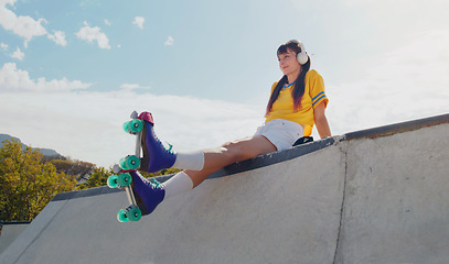 Image showing Relax, music and rollerblades with woman in skate park for summer break, streaming and sports. Fitness, peace and skating with girl listening to headphones in outdoors for hobby, freedom and peace