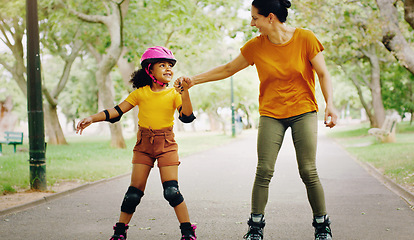 Image showing Mother, park and holding hands to rollerskate with girl child with care, learning and support. Interracial parent, teaching and woman with kid, smile and helping hand on road for skating on holiday