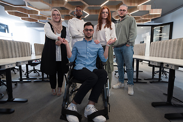 Image showing Young businessmen in a modern office extend a handshake to their business colleague in a wheelchair, showcasing inclusivity, support, and unity in the corporate environment.