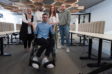 Image showing Young businessmen in a modern office extend a handshake to their business colleague in a wheelchair, showcasing inclusivity, support, and unity in the corporate environment.