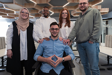 Image showing Young businessmen in a modern office extend a handshake to their business colleague in a wheelchair, showcasing inclusivity, support, and unity in the corporate environment.