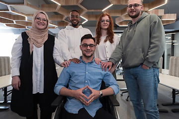 Image showing Young businessmen in a modern office extend a handshake to their business colleague in a wheelchair, showcasing inclusivity, support, and unity in the corporate environment.