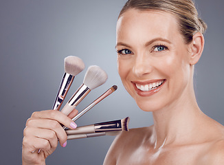 Image showing Face, tools for makeup and woman with smile, beauty and skin glow, portrait and foundation on studio background. Powder, cosmetics brush and skincare with shine, cosmetology and cosmetic care