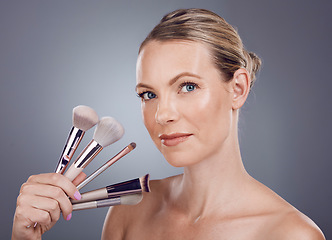 Image showing Face, tools for makeup and woman in portrait, beauty and skin glow with facial and foundation on studio background. Powder, cosmetics brush and skincare with shine, cosmetology and cosmetic care