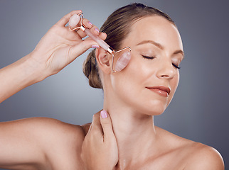 Image showing Woman, face roller and beauty of facial product of aesthetic skincare massage in studio. Female model, rose quartz treatment and wellness for natural cosmetics, crystal stone dermatology or salon spa