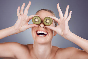 Image showing Kiwi, woman and cover eyes for beauty, skincare and wellness food on studio background. Happy model, smile and organic green fruits for natural cosmetics, detox and nutrition benefits of funny face