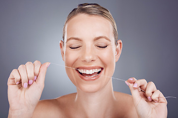 Image showing Floss, teeth and smile of woman in studio for beauty, healthy dental hygiene and background. Happy female model, tooth flossing and cleaning mouth for treatment, fresh breath and oral maintenance