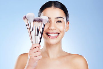 Image showing Beauty brushes, makeup and portrait of woman with smile on blue background for cosmetics, powder and foundation. Skincare, cosmetology and face of girl with brush for application, eyeshadow and salon