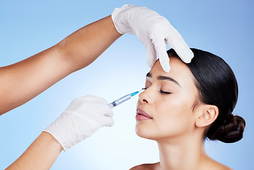 Image showing Plastic surgery, face and surgeon injection for beauty, filler and change for a woman in studio. Aesthetic model and doctor hands for cosmetic surgery, transformation or dermatology blue background