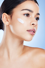 Image showing Woman, face and skincare moisturizer in cosmetics or beauty against a blue studio background. Female cheek with product, lotion or cream for facial treatment, collagen or healthy self care skin
