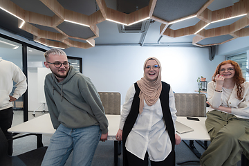 Image showing A group of young business professionals stands together, taking a well-deserved break from their busy workday, showcasing camaraderie, teamwork, and a moment of relaxation in their dynamic workplace