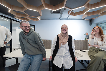 Image showing A group of young business professionals stands together, taking a well-deserved break from their busy workday, showcasing camaraderie, teamwork, and a moment of relaxation in their dynamic workplace