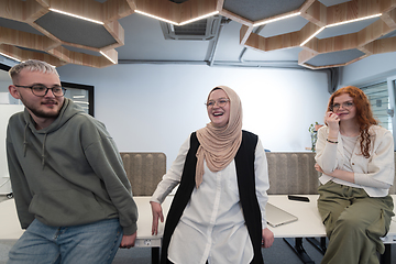 Image showing A group of young business professionals stands together, taking a well-deserved break from their busy workday, showcasing camaraderie, teamwork, and a moment of relaxation in their dynamic workplace