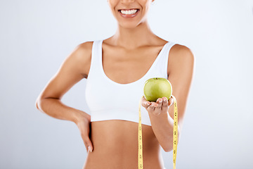 Image showing Detox, apple and tape measure with a fitness black woman in studio on a gray background for healthy eating. Exercise, fruit and wellness with a female posing to promote a lifestyle of health or diet