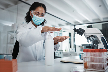 Image showing Science, covid or sanitizer with a doctor black woman at work in a laboratory to sterlize her hands. Medical, health and safety with a female scietist working in a lab for research or innovation